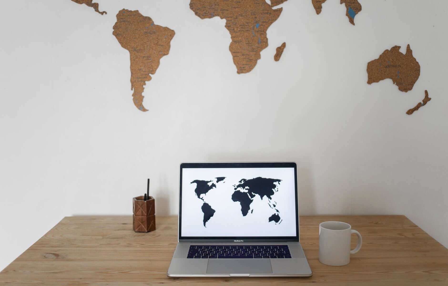 world map on wall and laptop near cup and container